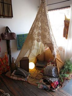 a teepee is sitting in the middle of a room with pillows and blankets on it