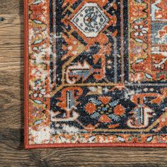 an orange and blue rug on a wooden floor with a wood table in the background