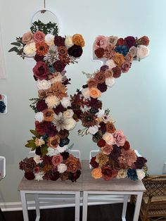 the letter k is made up of flowers and leaves on top of a wooden table