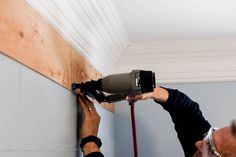 a man is using a drill to paint the ceiling