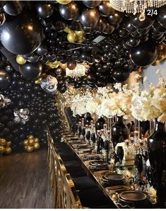 a long table is set with black and gold balloons