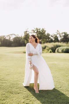 a woman in a white dress is standing on the grass