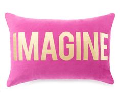 a pink and gold pillow with the word imagine printed on it, against a white background