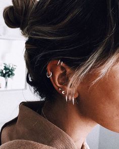 a woman with her hair in a bun is wearing earring and looking off to the side