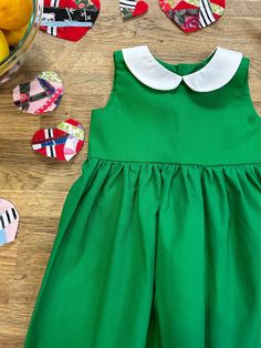 This classic, green cotton dress features a gathered skirt and white Peter Pan collar. Dress closes in the back with button closures.  Dress is made to order. Pinafore apron not included. **I have one ready-to-ship size 3t available directly on website here: https://wolfbanditpupbrigade.com/products/classic-green-dress-with-peter-pan-collar-sample-size-3t Classic Green Spring Dress, Classic Green Cotton Dress, Green Cotton Dress For Dress-up, Cotton A-line Dress With Box Pleat, Classic Cotton Dress For Dress-up Occasions, Classic Cotton Dresses For Dress-up, Classic Cotton Dresses For Dress-up Occasions, Cotton Dress With Peter Pan Collar For Garden Party, Dress With Peter Pan Collar