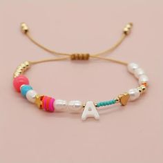 the initial bracelet is decorated with colorful beads and gold accents, along with a beaded letter