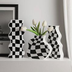 three black and white vases sitting on top of a shelf next to a framed photo