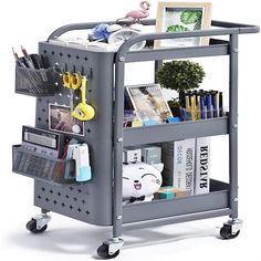 a gray cart filled with lots of books and office supplies on wheels next to a potted plant