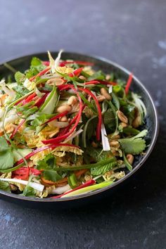 a black bowl filled with lots of veggies on top of a dark table