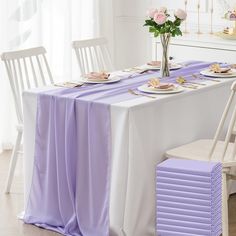 the table is set with plates and silverware on it, along with purple napkins