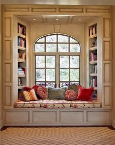 an image of a couch in front of a window with bookshelves on it