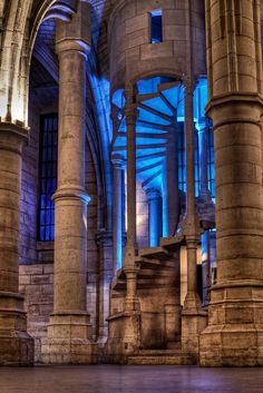 the interior of an old building with stone columns and blue light coming from it's windows