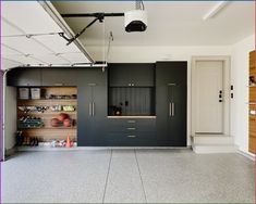 an empty garage with black cabinets and white flooring on the walls, along with hanging lights