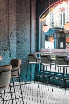 the interior of a restaurant with chairs and tables in front of an arched glass window