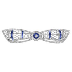 A truly beautiful white gold bow brooch set with diamonds and French cut sapphires. The milgraining of the metal edges allow the diamonds and gemstones to sparkle without competing with the reflected light from a highly polished white gold edge. Altogether a stunning piece. Brooch Information Metal: 14K White Gold Width: 15 mm. Length: 67 mm. Weight: 8.30 g. (approx. in total) Center Gemstones Type: Diamond Shape: Round Average Color: H Average Clarity: SI Size: 2 mm. Number: 1 Weight: 0.04 Carat (approx.) Accent Gemstones I Type: Sapphire Shape: French Cut Size: 2 mm. Number: 36 Weight: 2.25 Carat (approx.) Accent Gemstones II Type: Diamond Shape: Round Average Color: H Average Clarity: SI Size: 1 – 1.3 mm. Number: 152 Weight: 1.20 Carat (approx.) This brooch will be made to your order in Bow Brooch, French Cut, Estilo Art Deco, Art Deco Stil, Art Deco Style, High Jewelry, Deco Style, Art Deco Fashion, Diamond Shapes