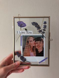 a person holding up a photo frame with flowers on it and the words i love you