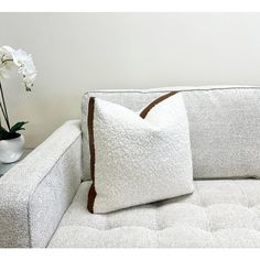 two white pillows sitting on top of a couch next to a vase filled with flowers