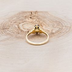 a gold ring sitting on top of a tree stump with a diamond in the middle