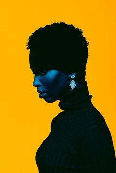 a woman with blue paint on her face and black hair is standing in front of an orange background