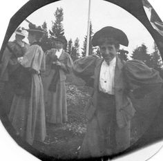 an old black and white photo of people dressed in period clothing, holding onto a flag