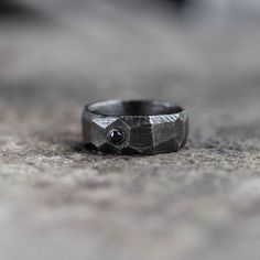 "A black oxidized sterling silver band ring for men with a natural black diamond 2.5mm in brutalist style. This raw ring is totally handcrafted, and can be also used as a textured wedding band. A great choice for a gift for him. --- MATERIALS & DIMENSIONS --- * High Quality 925 Sterling Silver * Black Oxidized finish * Natural Black Diamond 0.06ct * Width: 8mm --- SHIPPING --- All orders are shipped via FedEx Express for speed and security (delivery time to the US 3-5 days, Europe 1-2 days). Ple Black Oxidized Rings For Anniversary, Black Sterling Silver Rings With Single Cut Diamonds, Minimalist Hand Forged Black Rings, Black Oxidized Promise Ring, Modern Hand Forged Black Rings, Hand Forged Black Rings For Anniversary, Black Diamond Ring Men, Diamond Ring Men, Mens Black Diamond Rings