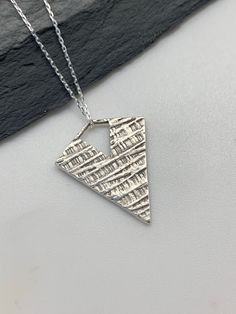 This modern silver triangle necklace has been entirely handmade using .999 fine silver. It has been cut from fine silver precious metal clay, textured, fired and oxidized. The pendant hangs from a sterling silver diamond cut cable chain. This lovely reversible pendant has a basket weave pattern on one side and a unique modern edgy striped deco pattern on the reverse side. Pendant size: approximately 1 x 3/4 inches Chain length: adjustable at 16 and 18 inches can also be customized to whatever le