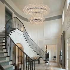 an elegant staircase with chandelier and rugs on the floor in front of it