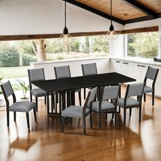 a dining room table and chairs in front of an open kitchen area with wood flooring