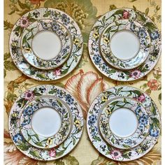 four plates with floral designs on them sitting on a table