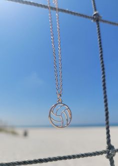 a volleyball ball is hanging from a chain on the beach with blue sky in the background