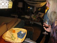 a woman holding a wine glass in her hand and looking at something on the table