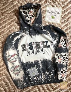 How cute is this mama hoodie!! Personalized with your kids names, can also make this for grandmas, aunts whoever!! Just message me Remember no 2 hoodies will be the exact same bleach pattern, and may have light spotting  All hoodies are depending on weather and may take a bit to make. Baseball Mama Outfit, Mama Hoodie Ideas, Baseball Mom Hoodie, Casual Personalized Hooded Hoodie, Baseball Season Graphic Print Hoodie, Casual Personalized Cotton Hoodie, Customizable Casual Sports Hoodie, Sporty Pre-shrunk Hoodie For Baseball Season, Casual Customizable Hoodie For Sports Events