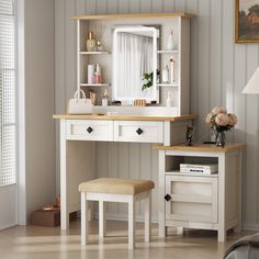 a white dressing table with a mirror and stool next to a window in a room