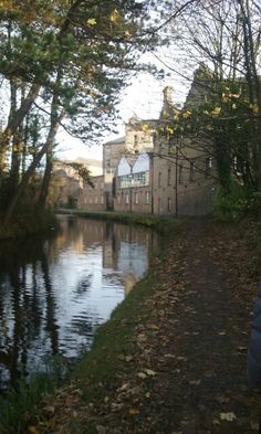 a person walking down a path next to a body of water in front of an old building