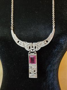 Gorgeous vintage long silver tone chain link necklace with a large stunning princess cut magenta stone in the middle. Very beautiful necklace with lots of character to add to your amazing outfit! The necklace itself is very ornate with lots of cut out deco. Looks very art deco style. Great gift idea for that special someone that collects unique and one of a kind jewelry. **Few slight scratches on the stone- please see all photos Necklace Drop 12 inches  Pendant 3.5inches x5inches Gemstone .75x . Silver Necklace With Rectangular Pendant For Formal Occasions, Formal Metal Necklace With Rectangular Pendant, Antique Sterling Silver Necklace With Jewels, Antique Sterling Silver Jeweled Necklaces, Antique Sterling Silver Jeweled Necklace, Antique Sterling Silver Necklaces With Jewels, Elegant Pink Engraved Necklace, Art Deco Sterling Silver Engraved Necklace, Silver Necklace With Rectangular Gemstone