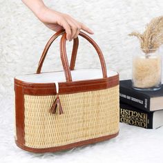 a person holding a brown and white bag next to a stack of books on a furry surface