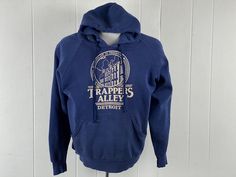 "Vintage 1970s, maybe ealy 80s hooded sweatshirt Hoodie. Made of blue poly/cotton. Detroit Michigan sweatshirt. TRAPPERS ALLEY was an area of Greektown in Downtown Detroit. I used to play pinball down there as a child. Now it has been reconstructed into a huge Casino. Has a front pocket and drawstring hood. No name label, size large. Actual measurements are:  48\" around the chest  42\" around the waist   22\" shoulder to shoulder  23\" shoulder  to cuff    25\" overall length, plus 12\" hood In good condition, slightly distressed with some paint and some spots." Michigan Sweatshirt, Downtown Detroit, Name Label, Vintage Hoodie, Name Labels, Sweatshirt Vintage, Vintage Hoodies, Detroit Michigan, No Name