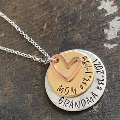 "Custom grandma necklace for a new grandma or one that's well established. Show your grandparent pride with this \"established\" mom and grandma necklace. 1\" handstamped silver alkeme tag is stamped \"Grandma est.\" with date you became (or will become) a grandma. 3/4\" solid brass disc stamped \"Mom est.\" with date you became a mom. 1/2\" copper heart charm. All pieces are hand stamped letter by letter in true artisan style. Edges are beveled and each has a brushed satin finish. Hangs from a Hand Stamped Round Pendant Necklace For Mom, Hand Stamped Round Pendant Necklace As Gift For Mom, Round Pendant Necklace With Hallmark For Mother's Day, Hand Stamped Round Pendant Necklace For Anniversary, Anniversary Hand Stamped Round Pendant Necklace, Adjustable Hand Stamped Necklaces For Anniversary Gift, Adjustable Hand-stamped Necklaces For Anniversary Gift, Hand Stamped Round Necklace For Mother's Day, Hand Stamped Round Necklaces For Mother's Day