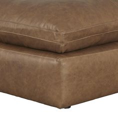 a brown leather ottoman sitting on top of a white floor