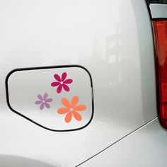 a white car with pink and orange flowers on it's side window sticker