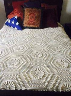 a white crocheted bedspread with an american flag pillow