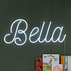 a neon sign that reads,'bella'on the wall next to children's books