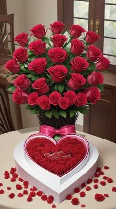 a heart shaped box filled with red roses on top of a table next to a bouquet of flowers