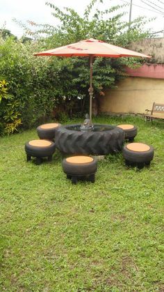 an umbrella is sitting on top of some tires in the grass with benches around it