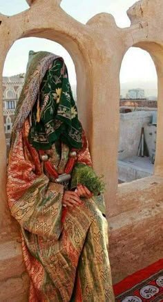 a woman sitting on top of a stone wall next to an arch in a building