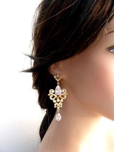 a close up of a woman's face wearing gold earrings with flowers on them