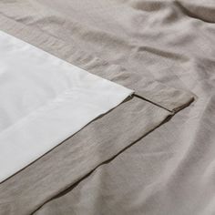 an unmade bed with white sheets and beige linens on top of each other