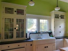 a kitchen with green walls and white cabinets