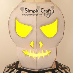 a paper mask with glowing yellow eyes and fangs on it's face is shown