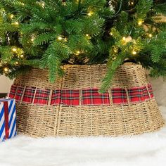 a small christmas tree in a basket next to a wrapped present box with lights on it